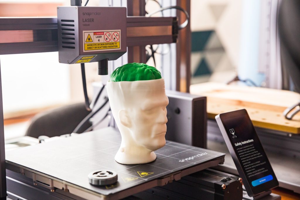 3д принтер і на його столі надрукована голова людини з білого пластику