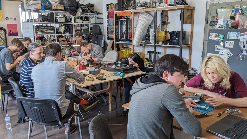 Чоловіки і жінки ремонтують різноманітні предмети під час ремонтного кафе в майстерні Хаклаб