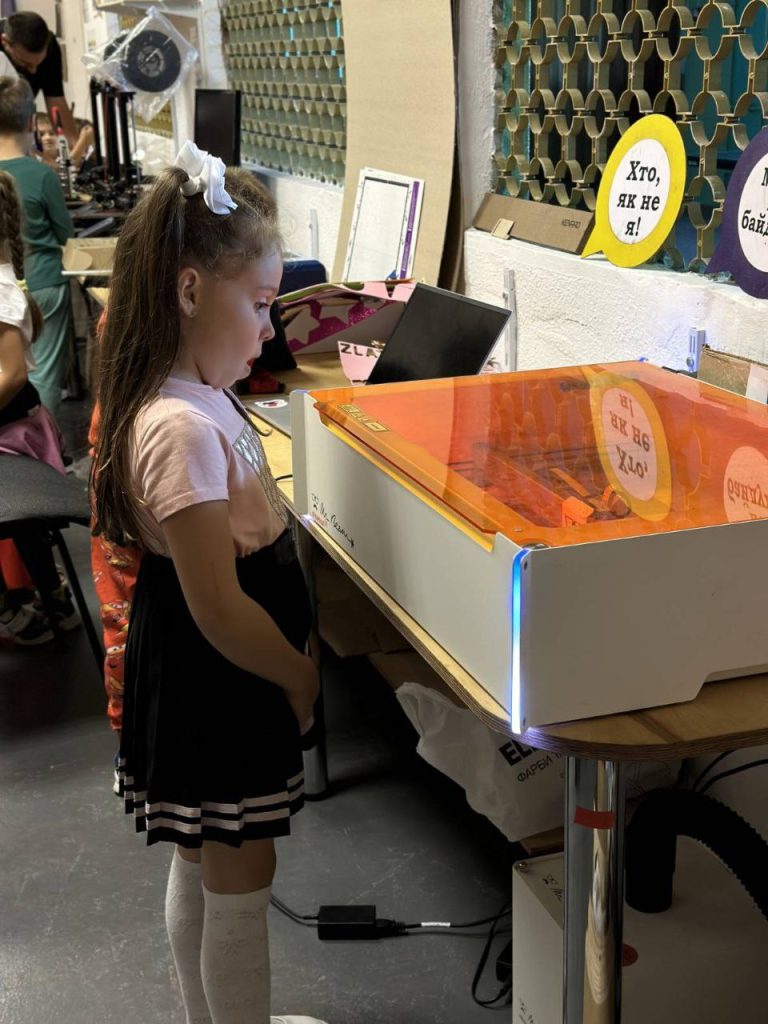 Дівчинка 6 років здивовано дивиться на роботу CNC лазера